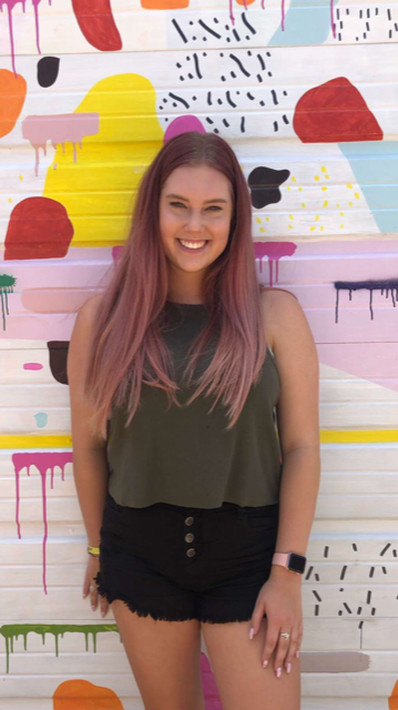 Kaylee Goodwin posing in inspiration alley with her newly dyed pink hair.