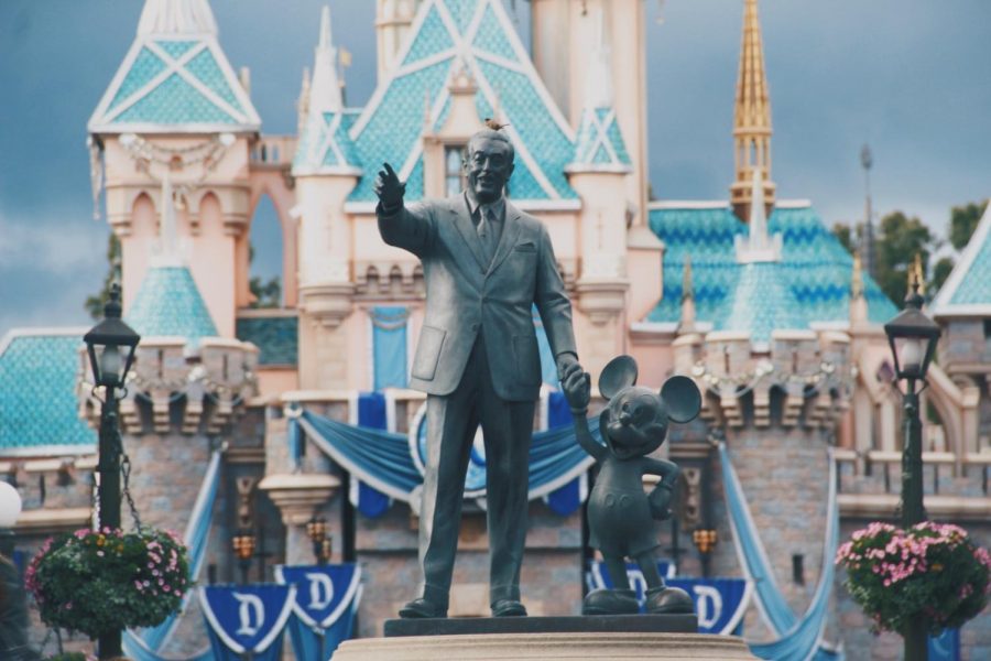 A statue of Walt Disney and Mickey Mouse is shown in front of the Cinderella Castle at Disneyland.