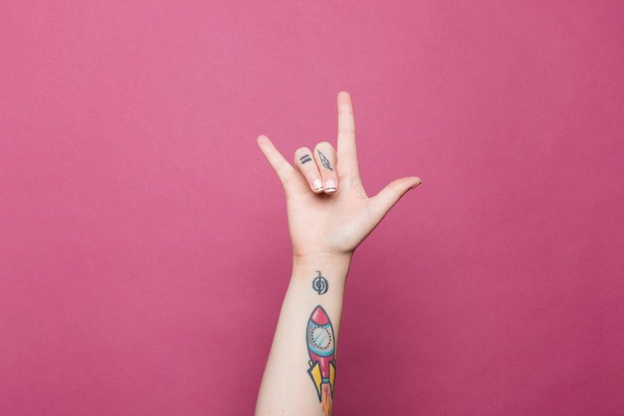 A tattoed hand doing the sign 