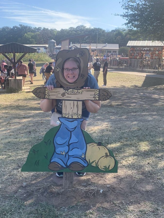 MacNeal at a fall festival posing with a scarecrow cutout.
