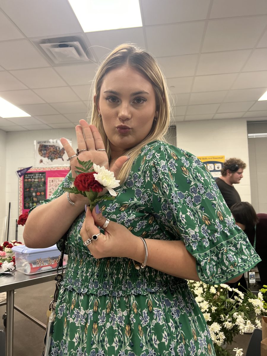 Ms.Weeks holding a boutonniere in floral design. 