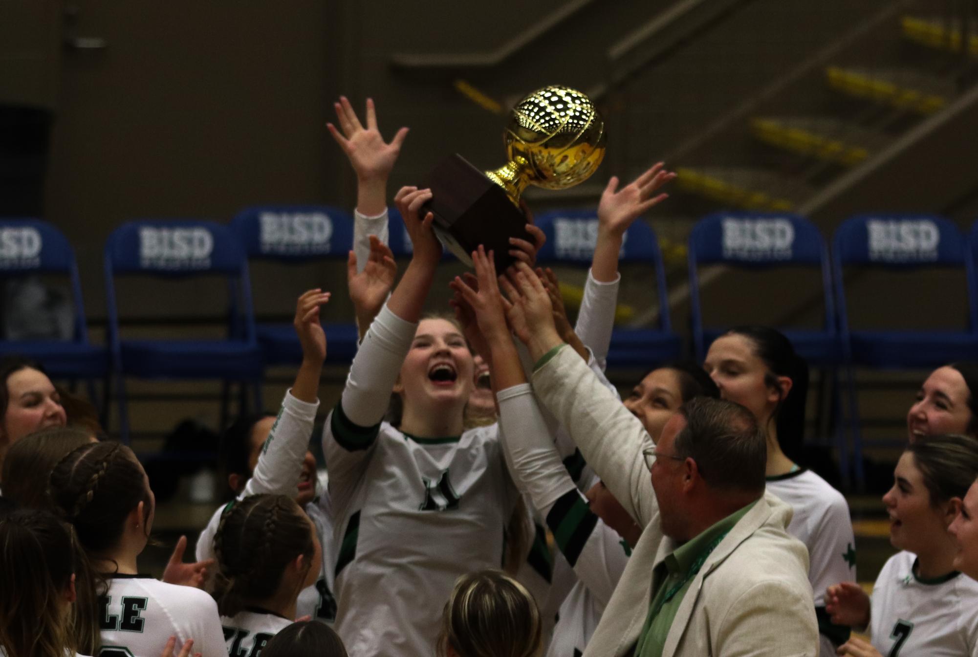 Volleyball hoists the Area Championship in the air along with Nate Driver