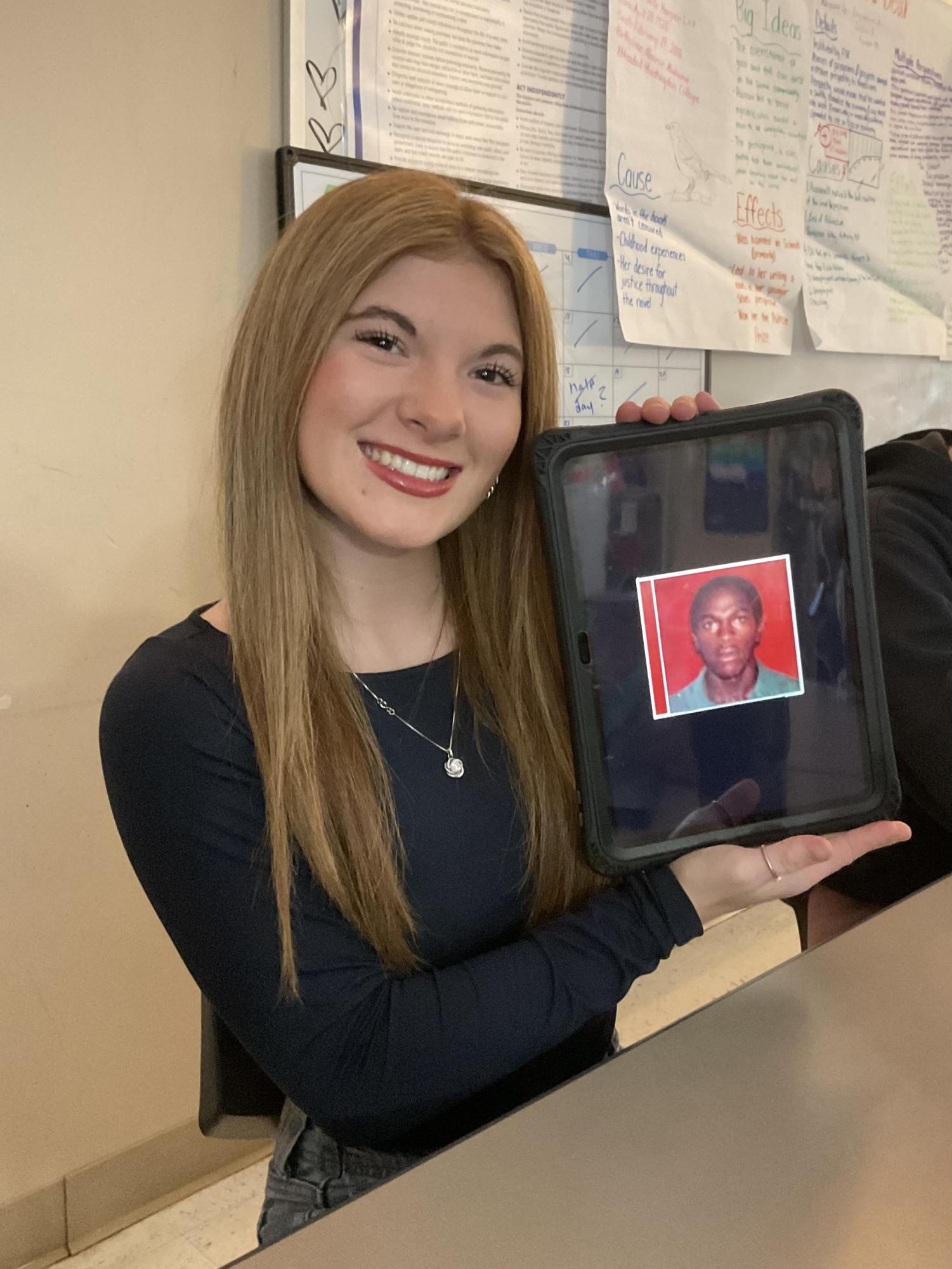 Junior Zoe Hopton holds a picture of Daniel Caesar's album cover. Album cover courtesy of Rough Trade.